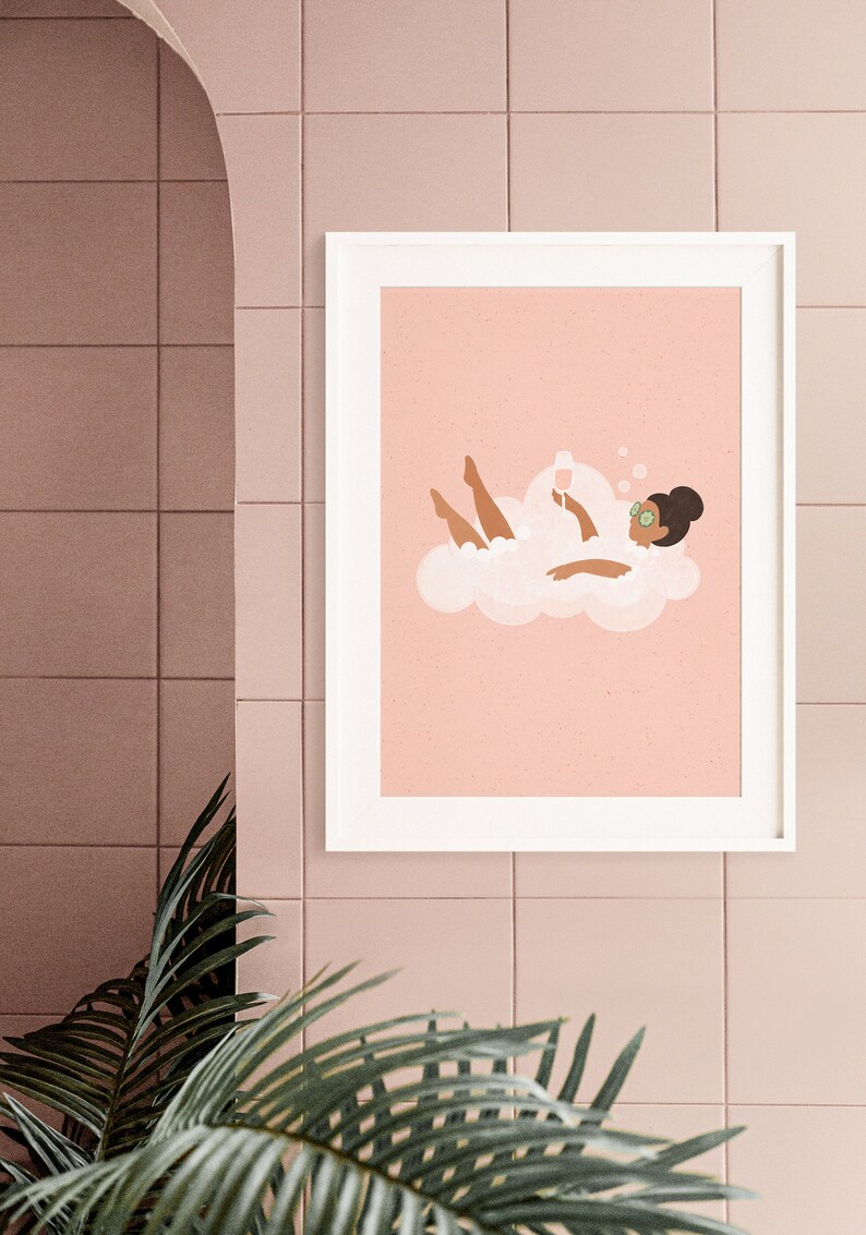 May include: A framed illustration of a person relaxing in a bubble bath with a glass of wine. The person is wearing a cucumber face mask and is surrounded by bubbles. The background is a light pink color.
