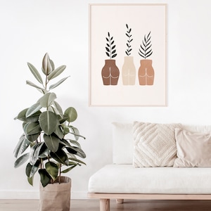 May include: A framed print with a minimalist design featuring three stylized figures with plants growing out of their heads. The figures are in shades of brown, beige, and peach.