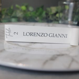 May include: White table number card with the text "Table 2 LORENZO GIANNI" in gray lettering.