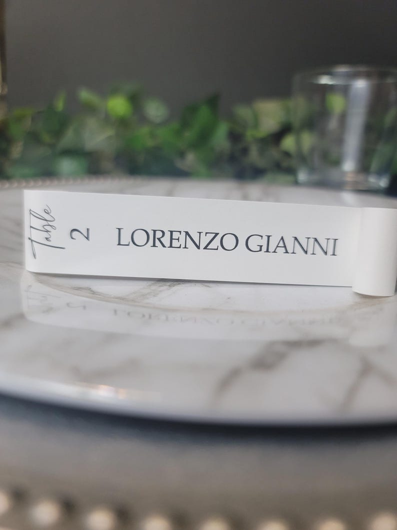 May include: White table number card with the text "Table 2 LORENZO GIANNI" in gray lettering.