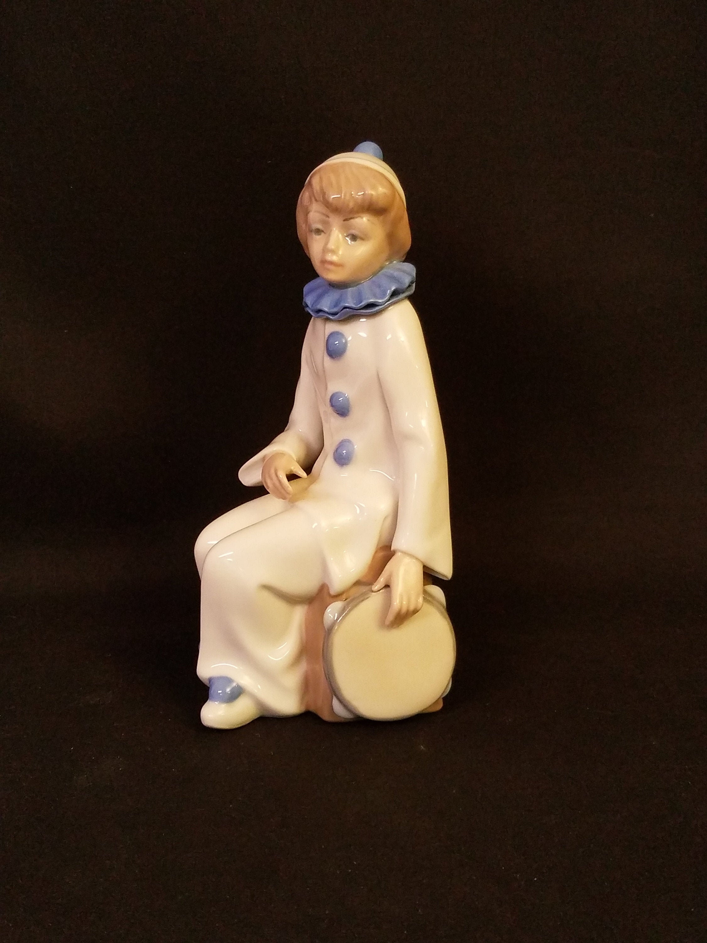 Casades porcelain hand painted figurine of a boy in clown clothes with a tambourine at his side Made in Spain The Other Porcelain