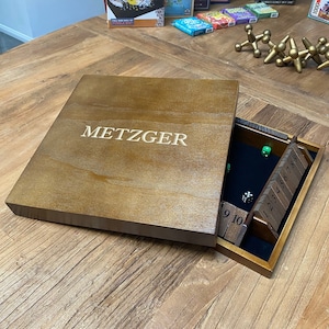 May include: A wooden game box with the word "METZGER" engraved on the lid. The box is open and reveals a wooden game board with numbered tiles and dice.
