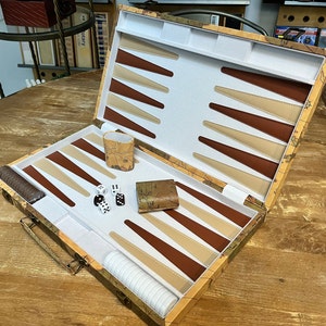May include: A brown and beige backgammon set with a world map design. The set includes dice, a cup, and checkers. The board is open and ready to play.
