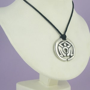 May include: A silver pendant necklace with a circular design featuring a stylised human figure. The necklace is on a black cord.