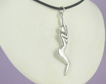 Puede incluir: Collar con colgante plateado que representa una figura humana estilizada. El colgante cuelga de un cordón negro. La figura tiene una forma alargada y curvada con los brazos levantados por encima de la cabeza.