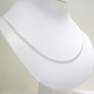 May include: A silver chain necklace on a white display stand. The chain is a curb style and is about 18 inches (46 cm) long.
