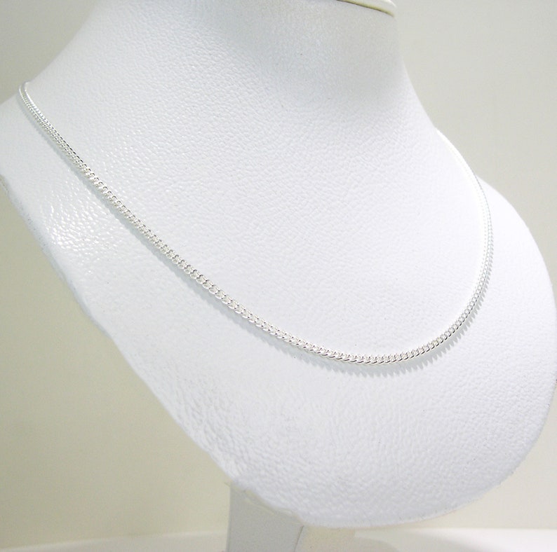 May include: A silver chain necklace on a white display stand. The chain is a curb style and is about 18 inches (46 cm) long.