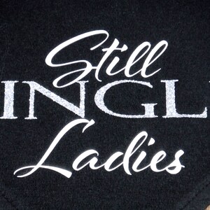 May include: Black fabric bandana with white glitter lettering that reads "Still Single Ladies".
