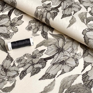 Coated cotton oilcloth with a floral pattern in gray tones on ecru white, sold by the cut, sold in multiples of 10cm (X 142cm wide)