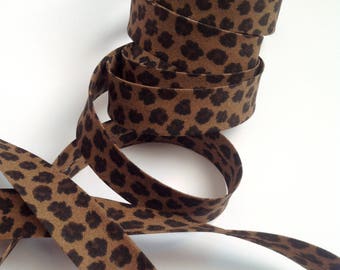 Cinta al bies de algodón preplegada de 2 cm de ancho con estampado de leopardo en marrón y negro, se vende en rollos de 2 m, 5 m, 10 m y 25 m.