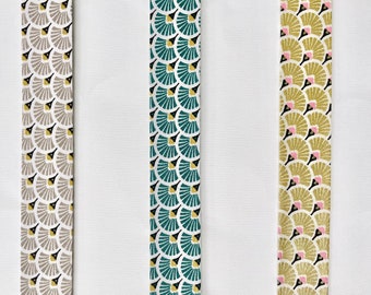 Motivo sbieco con eleganti ventagli stampati in grigio talpa, blu-verde e oro, rilegatura in sbieco pre-piegata a 2 strati larga 27 mm, venduta al metro