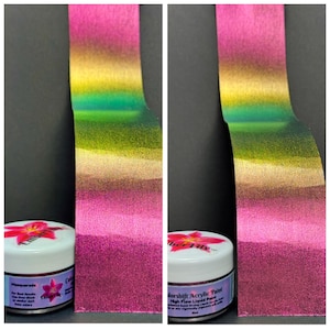 Pu&ograve; includere: Due immagini mostrano un test di gradiente di colore di vernice acrilica. La striscia di vernice passa dal rosa all'oro, al verde e di nuovo al rosa. Due piccoli barattoli di vernice sono in basso, uno con l'etichetta "Masquerade" e l'altro "Colorshift Acrylic Paint."