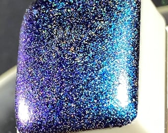 May include: A square, iridescent blue and purple glitter resin piece with a white base.