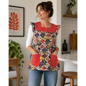 May include: A sleeveless apron featuring a square neckline and two front pockets, all accented with a red and white polka dot pattern. The main body displays a colorful patchwork design of floral and geometric motifs in blue, yellow, and red.