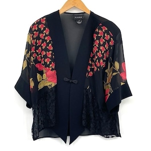 May include: Black open-front jacket with floral print panels featuring red roses and green leaves. The jacket has a black lace trim at the bottom and a decorative closure. The brand name "Virgo" is visible on the label.
