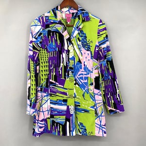 May include: A long-sleeved blazer featuring a vibrant, abstract geometric print in shades of lime green, royal blue, black, and pale pink. The jacket has a notched collar, a front button closure with four round buttons, and a structured fit.
