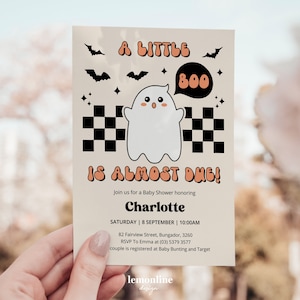 Peut inclure: Une invitation de f&ecirc;te pr&eacute;natale de couleur beige clair avec un fant&ocirc;me de dessin anim&eacute; portant un motif &agrave; carreaux noir et blanc. L'invitation indique "A Little Boo Is Almost Due!" et comprend le nom Charlotte, la date, l'heure et le lieu de l'&eacute;v&eacute;nement.