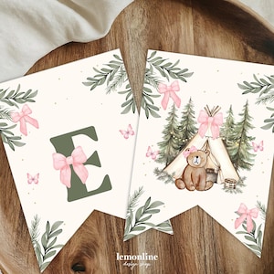 May include: Two banner flags with a woodland theme. One flag features the letter "E" with a pink bow. The other flag shows a bear in front of a tent, surrounded by trees and butterflies. The flags have a cream background with green leaves.