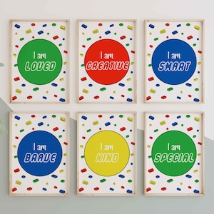 May include: Six framed art prints with positive affirmations. Each print features a colorful circle with a word like "Loved" or "Creative" and a background of toy blocks. The frames are light brown.