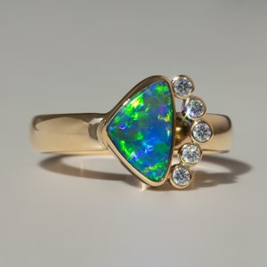 May include: A gold ring with a triangular green and blue opal gemstone and a row of small diamonds.