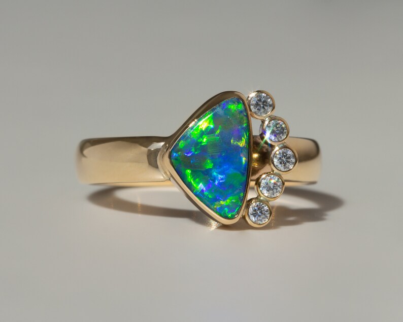 May include: A gold ring with a triangular green and blue opal gemstone and a row of small diamonds.