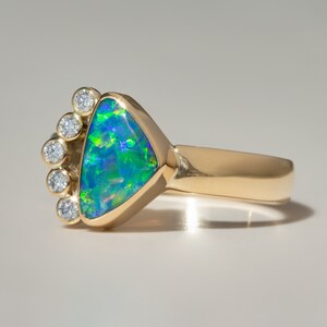 May include: A gold ring with a triangular green opal gemstone surrounded by a halo of small diamonds.