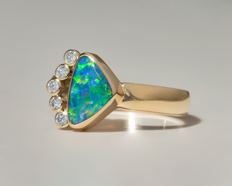 May include: A gold ring with a triangular green opal gemstone surrounded by a halo of small diamonds.