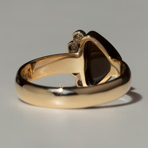 May include: A gold ring with a dark brown gemstone and small diamonds set in the band.