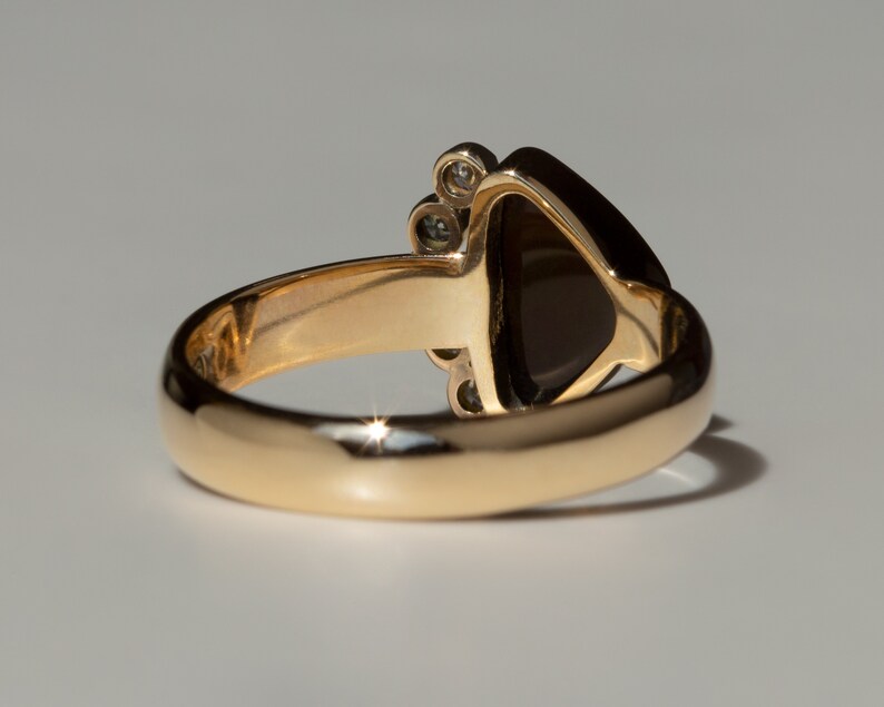 May include: A gold ring with a dark brown gemstone and small diamonds set in the band.