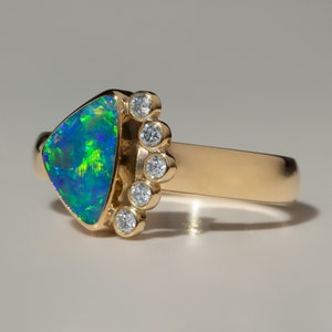 May include: A gold ring with a triangular green and blue opal gemstone and a row of small diamonds set in the band.