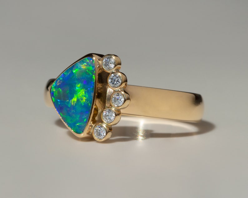 May include: A gold ring with a triangular green and blue opal gemstone and a row of small diamonds set in the band.