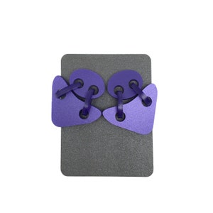 May include: Purple lacing toy with two pieces that are shaped like a teardrop and a circle. The toy is on a gray background.