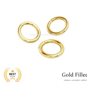 Op de afbeelding: Drie goudgevulde springringen worden getoond tegen een witte achtergrond. De ringen zijn cirkelvormig met een kleine opening. De tekst "Gold Filled" staat onder de ringen, samen met de woorden "FINDINGS - ACCESORIOS - APPRETS".