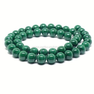 Peut inclure: Un brin de perles rondes en malachite verte. Les perles sont lisses et polies, avec un aspect naturel et terreux.