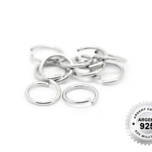 May include: A close-up of a pile of silver jump rings. The rings are all the same size and are made of 925 sterling silver. The rings are used for jewelry making and crafting.