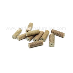 May include: A selection of cylindrical wooden beads with a natural, textured finish. Each bead is a light brown colour with darker brown graining, and has a hole through the centre. The beads are scattered on a white background.