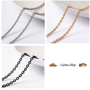 May include: Three chain necklaces in silver, gold, and black. The chains are on white surfaces. The chains are all the same style, with small, round links.