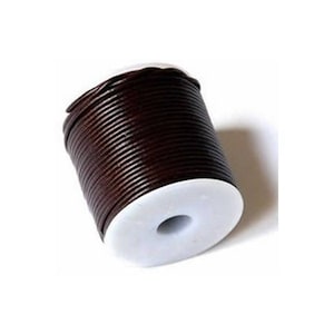 Può includere: Un rotolo di cordoncino in pelle marrone avvolto attorno a una bobina di plastica bianca.