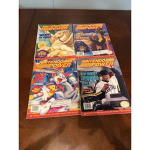 May include: Four vintage Nintendo Power magazines. Covers feature "Secret of Mana", "Aladdin", Bugs Bunny, and Ken Griffey Jr. The magazines have colorful graphics and text, with the Nintendo Power logo at the top.