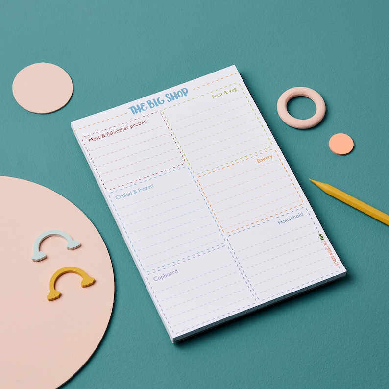 May include: A white notepad with a colorful grocery list template. The notepad has sections for "Meat & fish/other protein", "Fruit & veg", "Chilled & frozen", "Bakery", "Cupboard", and "Household".