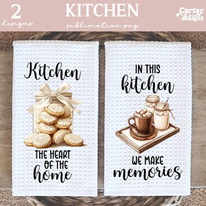 May include: Two white kitchen towels with black text and illustrations. The first towel says "Kitchen, The heart of the home" and features a jar of cookies. The second towel says "In this kitchen we make memories" and features a cup of hot chocolate and two jars of marshmallows.