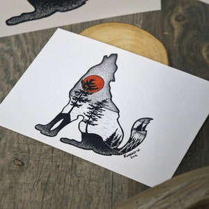 May include: Black and white illustration of a wolf with a forest scene inside its silhouette. The wolf is sitting with its head turned to the side. A red sun is visible in the background.