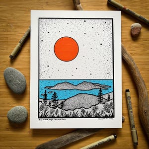 May include: A black and white landscape art print with an orange sun, blue lake, and dotted sky. The artwork includes the text "Pic Island, Mego Provincial Park" and "Kondrat, W. 2016". The print is on white paper.