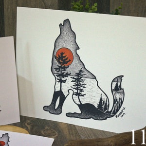 May include: Black and white illustration of a wolf howling at a red sun. The wolf's silhouette is filled with a forest scene, including trees and a lake. The artwork is signed "Kamarad" and dated "2019".