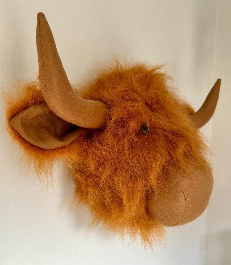 Peut inclure: Une t&ecirc;te de vache Highland en peluche marron &agrave; monter au mur. La vache a une crini&egrave;re longue et duveteuse et un nez marron. Les cornes sont en feutre et sont courb&eacute;es.
