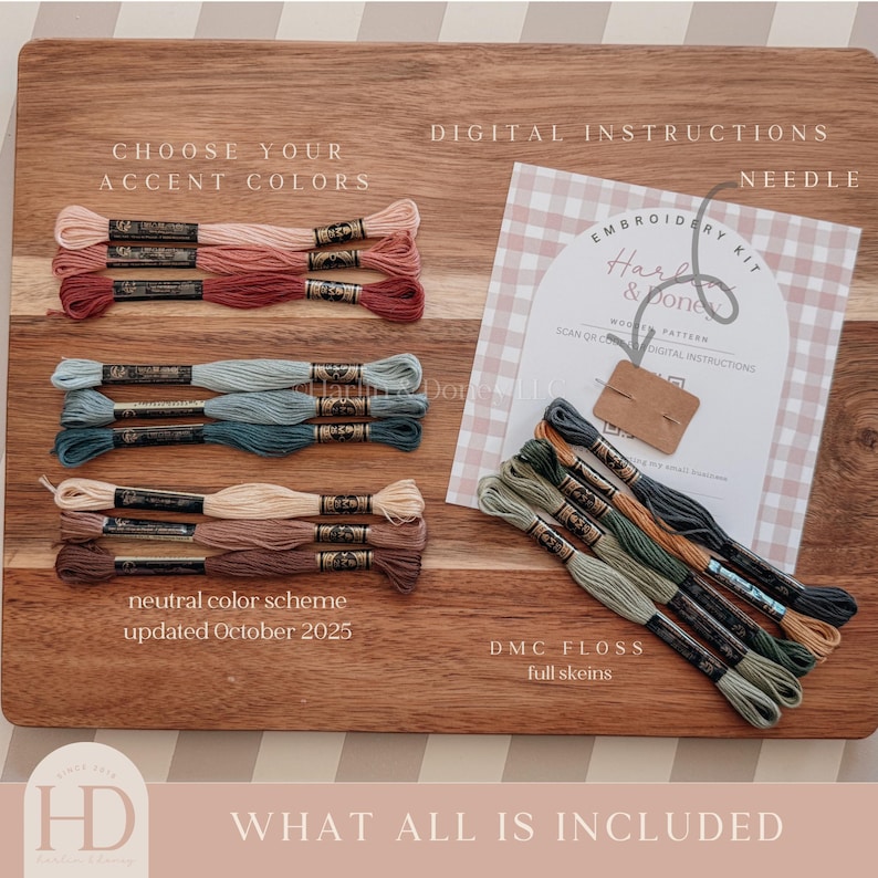 May include: An embroidery kit with DMC floss in various colors, including pinks, blues, and greens, arranged on a wooden board. The kit includes digital instructions and a needle. Text on the board reads "Choose Your Accent Colors" and "DMC Floss".