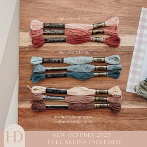 May include: A wooden surface displays embroidery floss in pink, blue, and neutral color schemes. The text "pink color scheme", "blue color scheme", and "neutral color scheme" are above the floss. The text "NEW OCTOBER 2025 - FULL SKEINS INCLUDED!" is at the bottom.