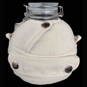 May include: A white canvas jar with a glass lid and a metal clasp. The jar is shaped like a baseball cap and has a white fabric strap.