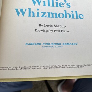 Puede incluir: Una portada de libro con el t&iacute;tulo "Willie's Whizmobile" de Irwin Shapiro. La portada es blanca con texto azul y una ilustraci&oacute;n azul de un coche. El libro est&aacute; publicado por Garrard Publishing Company en Champaign, Illinois.