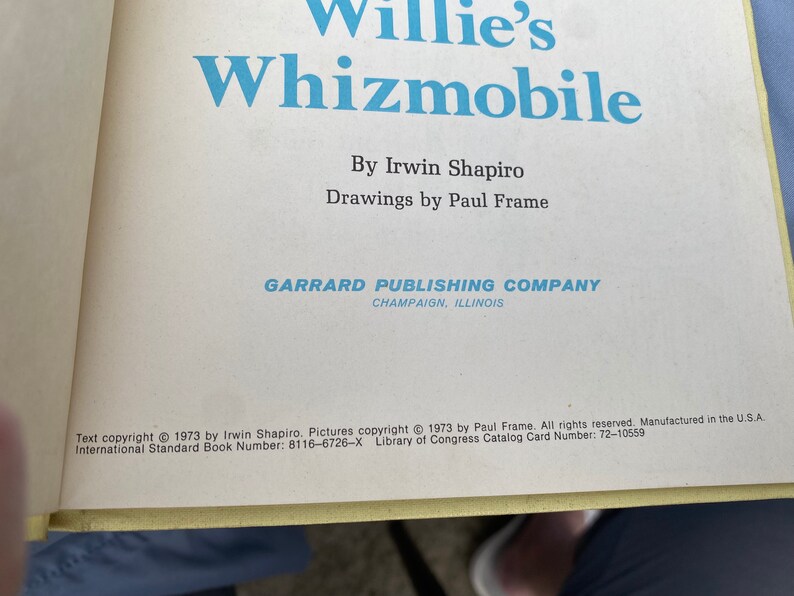 Puede incluir: Una portada de libro con el t&iacute;tulo "Willie's Whizmobile" de Irwin Shapiro. La portada es blanca con texto azul y una ilustraci&oacute;n azul de un coche. El libro est&aacute; publicado por Garrard Publishing Company en Champaign, Illinois.